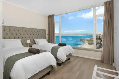 a hotel room with two beds and a large window at ZenDen Destinations' Seaside Sanctuary Suite in Strand