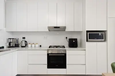 a white kitchen with a stove and a microwave at ZenDen Destinations' Seaside Sanctuary Suite in Strand