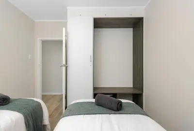 a bedroom with two beds and a mirror at ZenDen Destinations' Seaside Sanctuary Suite in Strand