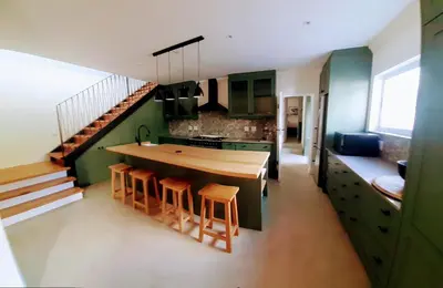 a kitchen with green cabinets and a kitchen island with stools at 3 Jongens Villa in Voëlklip