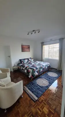 a bedroom with a bed and a couch and a window at Acanthus Circle in Cape Town