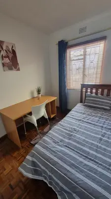 a bedroom with a bed and a desk and a window at Acanthus Circle in Cape Town