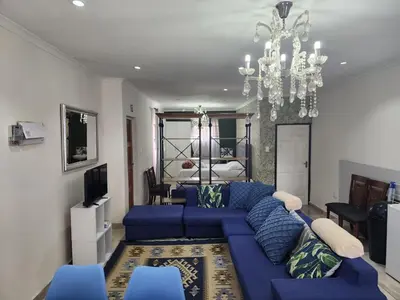 a living room with a blue couch and a chandelier at Tia Maria bachelor apartment in Cape Town