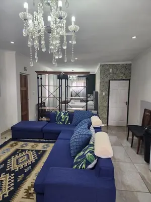 a living room with a blue couch and a chandelier at Tia Maria bachelor apartment in Cape Town