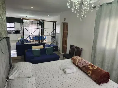 a bedroom with a bed and a couch and a chandelier at Tia Maria bachelor apartment in Cape Town