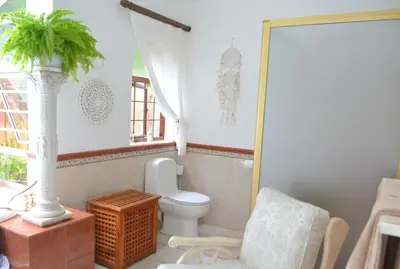 a bathroom with a toilet and a chair at Lovely Family Home in the Winelands in Cape Town