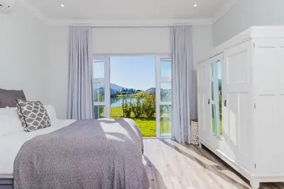 a bedroom with a bed and a large window at Val de Vie in Simondium