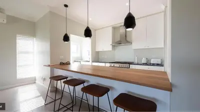 a kitchen with white cabinets and a counter with stools at Val de Vie in Simondium