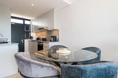 a kitchen with a glass table and two blue chairs at Burmeister 302 - Beach Front Views with Onsite Parking in Cape Town