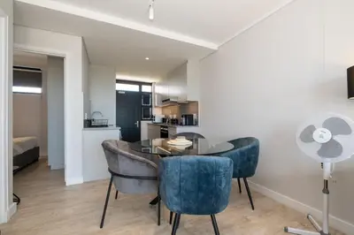 a dining room with a table and some blue chairs at Burmeister 302 - Beach Front Views with Onsite Parking in Cape Town