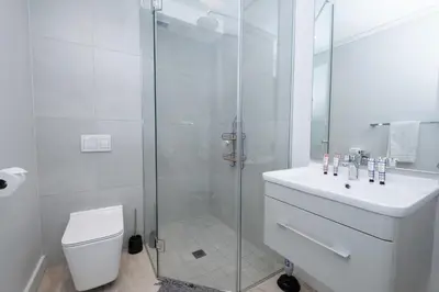 a bathroom with a shower and a toilet and a sink at Burmeister 302 - Beach Front Views with Onsite Parking in Cape Town