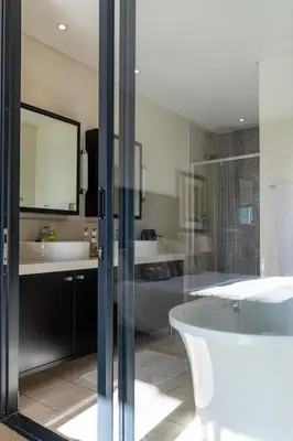 a bathroom with a tub and two sinks and a bath tub at Skyline Serenity - Knightsbridge in Cape Town