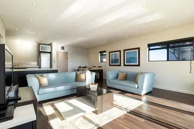 a living room with two blue couches and a table at Skyline Serenity - Knightsbridge in Cape Town