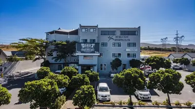 an apartment building with cars parked in a parking lot at Budapest Boutique Hotel in Edgemead
