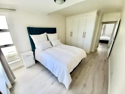 a bedroom with a large white bed and a mirror at Whale Rock Estate Four 1 in Hermanus