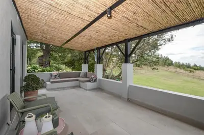 a screened in porch with a couch and chairs at 4 Bedroom Farm House in Brackenfell