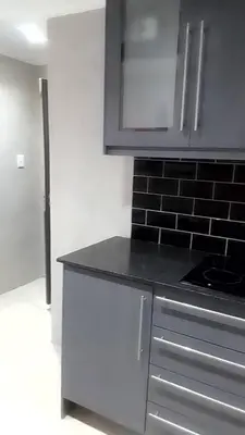 a kitchen with white cabinets and a black brick wall at Sisonke Guest House in Cape Town