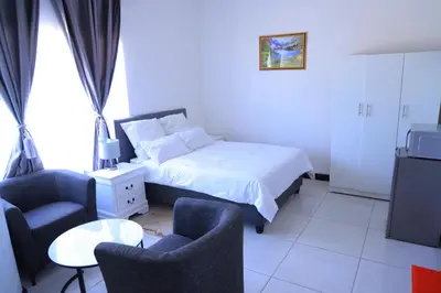 a bedroom with a bed and two chairs and a tv at paradise guest house in Cape Town