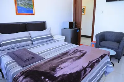 a bedroom with a large bed and a chair at paradise guest house in Cape Town
