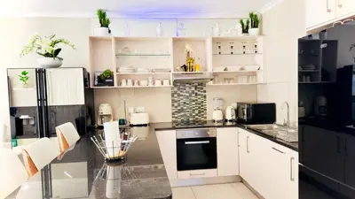 a kitchen with white cabinets and black appliances at Luxury 2bedrooms house in Cape Town