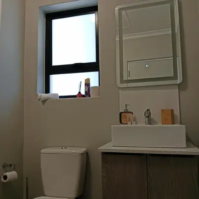 a bathroom with a toilet and a sink and a window at The Cozy Nest in Cape Town