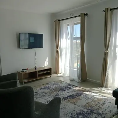 a living room with a tv and a couch and window at The Cozy Nest in Cape Town