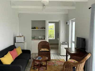 a living room with a couch and a table at Otter Cottage in Pringle Bay in Pringle Bay