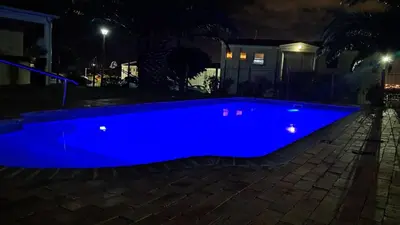 a blue swimming pool at night at Gordon's bay - Sea view apartment in Cape Town