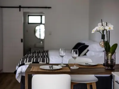 a bedroom with a bed and a table with wine glasses at Zonnekus Guesthouse in Cape Town