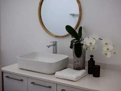a bathroom with a sink and a mirror and flowers at Zonnekus Guesthouse in Cape Town