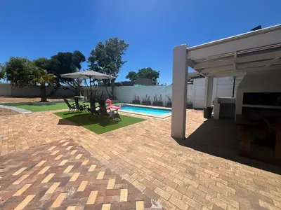 a patio with a table and an umbrella and a pool at Luxury 14 sleeper villa Lamsyh in Cape Town