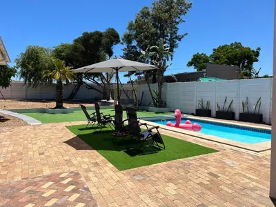 a pool with chairs and an umbrella next to a swimming pool at Luxury 14 sleeper villa Lamsyh in Cape Town