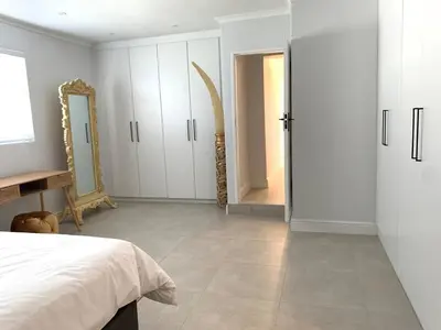 a white bedroom with a bed and a mirror at Luxury 14 sleeper villa Lamsyh in Cape Town