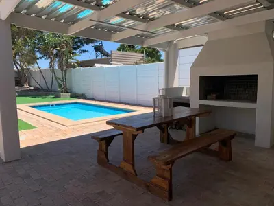 a patio with a wooden table and a swimming pool at Luxury 14 sleeper villa Lamsyh in Cape Town