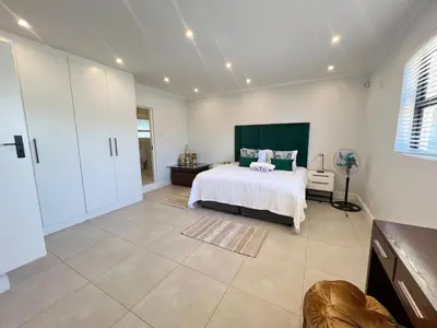 a bedroom with a bed with a green headboard at Luxury 14 sleeper villa Lamsyh in Cape Town