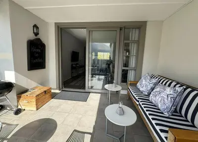 a living room with a couch and two tables at Le Bourgette - Close to Town With Great Views in Franschhoek