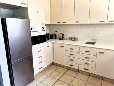 a kitchen with white cabinets and a refrigerator at Sunny Mountain View in Stellenbosch