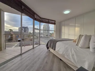 a bedroom with a large bed and a large window at Spacious 3Bed 2bath sleep 8 Beachfront Apartment with Table Mountain and Ocean view in Cape Town