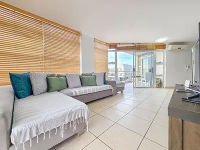 a living room with a couch and a large window at Spacious 3Bed 2bath sleep 8 Beachfront Apartment with Table Mountain and Ocean view in Cape Town
