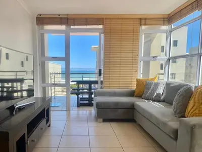 a living room with a couch and a view of the ocean at Spacious 3Bed 2bath sleep 8 Beachfront Apartment with Table Mountain and Ocean view in Cape Town