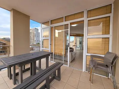 a dining room with a table and chairs on a balcony at Spacious 3Bed 2bath sleep 8 Beachfront Apartment with Table Mountain and Ocean view in Cape Town