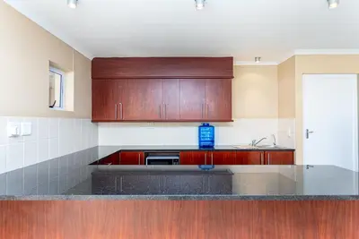 a kitchen with wooden cabinets and a counter top at Villa Italia 933 by CTHA in Cape Town