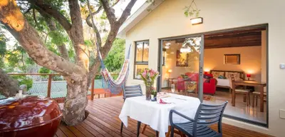 a table and chairs on a deck with a tree at TreeTop Apartment Cape Town in Cape Town