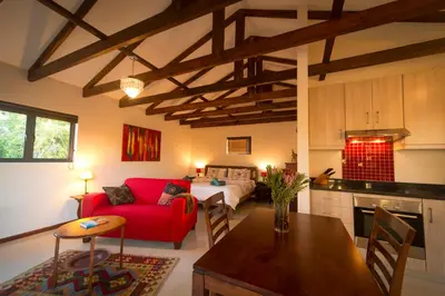 a living room with a red couch and a kitchen at TreeTop Apartment Cape Town in Cape Town