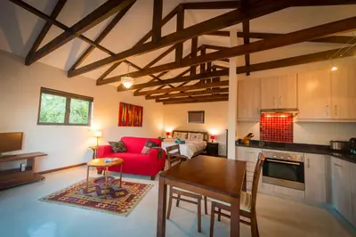 a kitchen and a living room with a red couch at TreeTop Apartment Cape Town in Cape Town