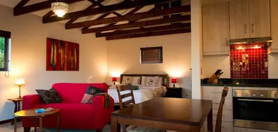 a living room with a red couch and a bedroom at TreeTop Apartment Cape Town in Cape Town