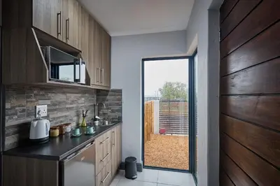 a kitchen with wooden cabinets and a sink and a window at Peppertree Place in Cape Town