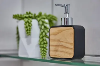 a soap dispenser on a glass shelf next to a vase at Peppertree Place in Cape Town
