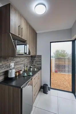 a kitchen with wooden cabinets and a large window at Peppertree Place in Cape Town