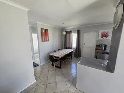 a dining room with a table and a kitchen at Watershed Self-Catering in Wolseley